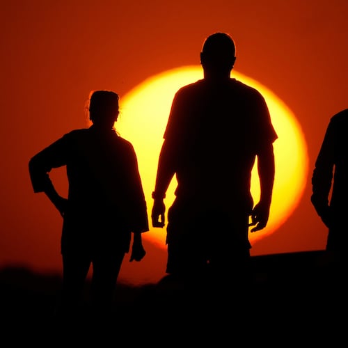 FILE - People watch the sunset from the Liberty Memorial grounds in Kansas City, Mo., May 12, 2025. (AP Photo/Charlie Riedel, File)