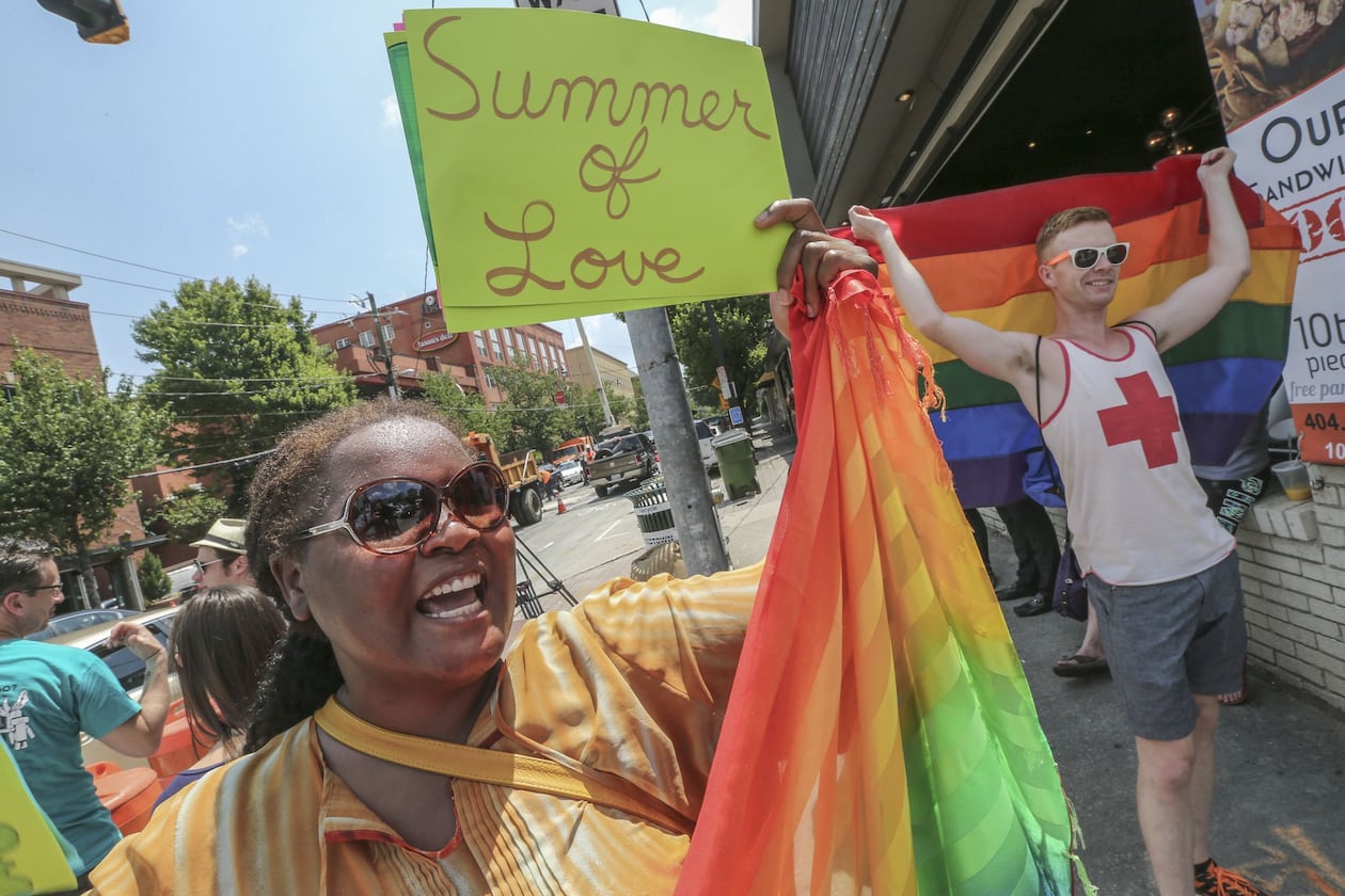 Audrey Miles (left) and Matt Bass (right) joined supporters of gay marriage that spontaneously gathered at 10th and Piedmont in Atlanta on June 26, 2015, to celebrate the U.S. Supreme Court’s ruling that same-sex couples have a constitutional right to marry. (AJC 2015)