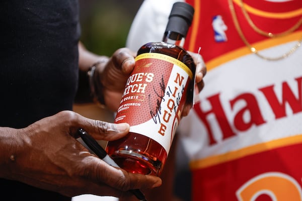 Wilkins holds a signed bottle of "Nique's Batch." (Natrice Miller/AJC)