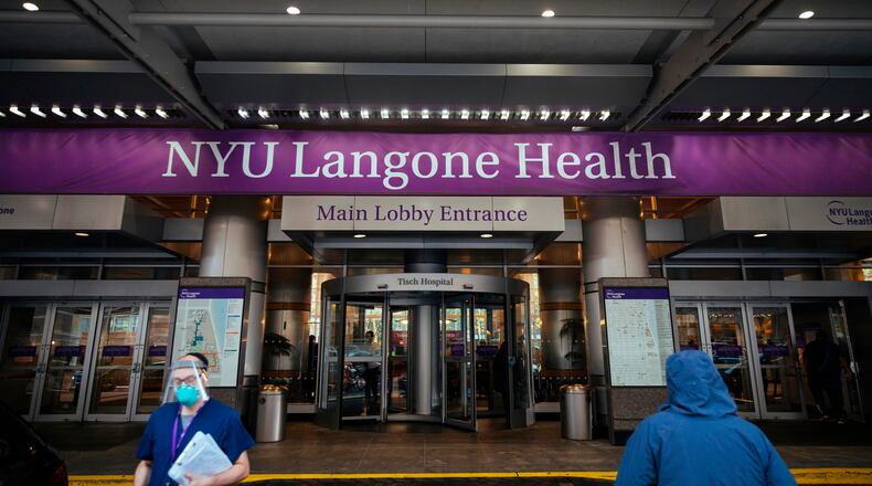 FILE - Health care workers walk in and out of the entrance at NYU-Langone Hospital on Dec. 14, 2020, in New York. (AP Photo/Kevin Hagen, File)