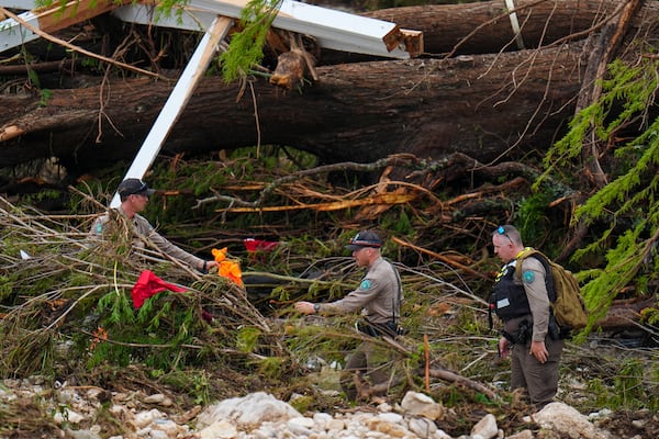 Officials with the Texas Game Warden comb through debris along the banks of the Guadalupe River after a flash flood swept through the area Saturday, July 5, 2025, in Hunt, Texas. (AP Photo/Julio Cortez)
