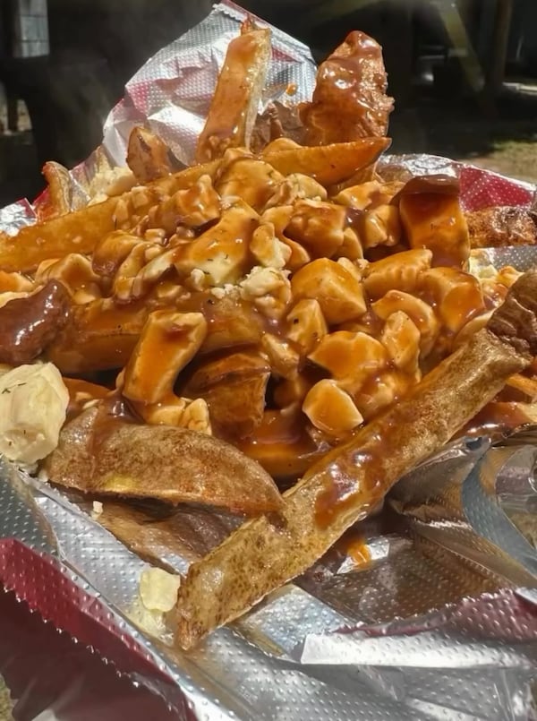 Poutine, french fries with cheese curds covered in brown gravy, sits on a tinfoil-covered tray