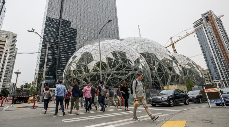 Pedestrians walk past a recently built trio of geodesic domes that are part of the Seattle headquarters for Amazon. The online retail giant said it was searching for a second headquarters in North America in 2017, a huge new development that would cost as much as $5 billion to build and run, and house as many as 50,000 employees. (Stuart Isett/The New York Times)
