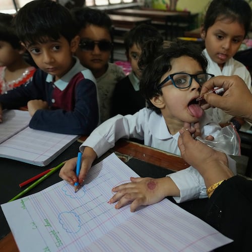 A health worker administers a polio vaccine to a child at a school in Lahore, Pakistan, Monday, April 13, 2026. (AP Photo/K.M. Chaudary)
