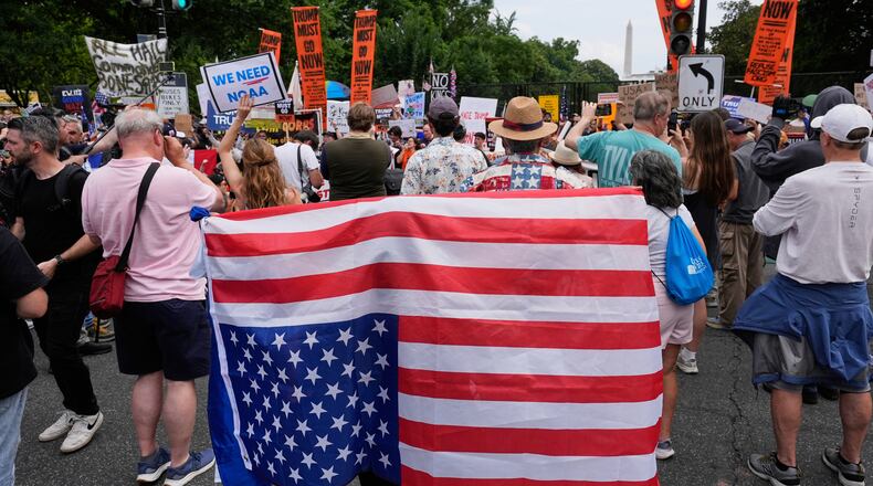 FILE - A demonstrator carries an American flag upside-down near the White House during a protest taking place on the day of a military parade commemorating the Army's 250th anniversary, coinciding with President Donald Trump's 79th birthday, June 14, 2025, in Washington. (AP Photo/Alex Brandon, File)