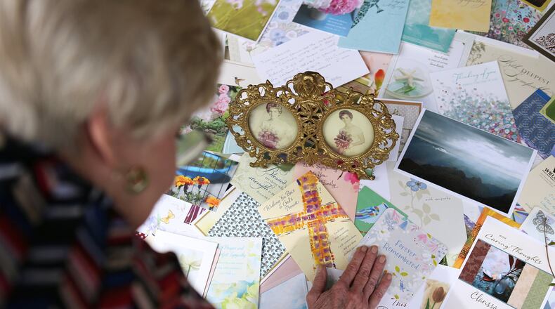 Clarissa Strickland, whose sister Nan Durrett, 74, died last month after developing a fever and cough at an assisted living facility, looks over the many dozens of sympathy cards she has placed around framed photographs of herself (left) and her sister (right) at her home in Lilburn. The family believes Durrett didn’t receive adequate care at the facility. When she was hospitalized, a physician told the family Durrett had COVID-19. (Curtis Compton / ccompton@ajc.com)