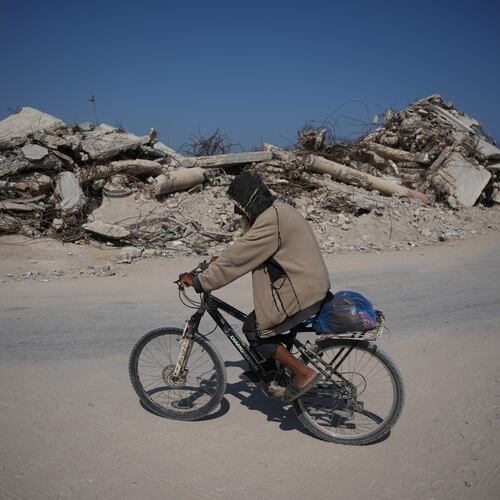 A Palestinian man rides his bicycle by the rubble of buildings that were destroyed during the Israel Hamas war, in Khan Younis, southern Gaza Strip, Friday, July 31, 2026. (AP Photo/Abdel Kareem Hana)