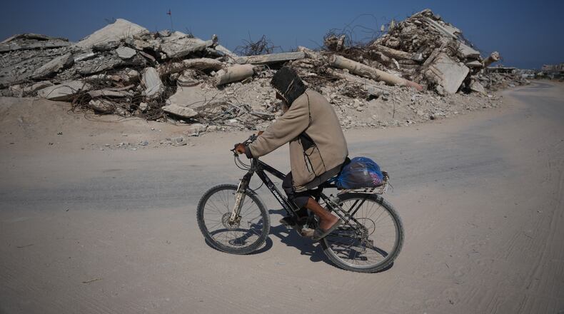 A Palestinian man rides his bicycle by the rubble of buildings that were destroyed during the Israel Hamas war, in Khan Younis, southern Gaza Strip, Friday, July 31, 2026. (AP Photo/Abdel Kareem Hana)