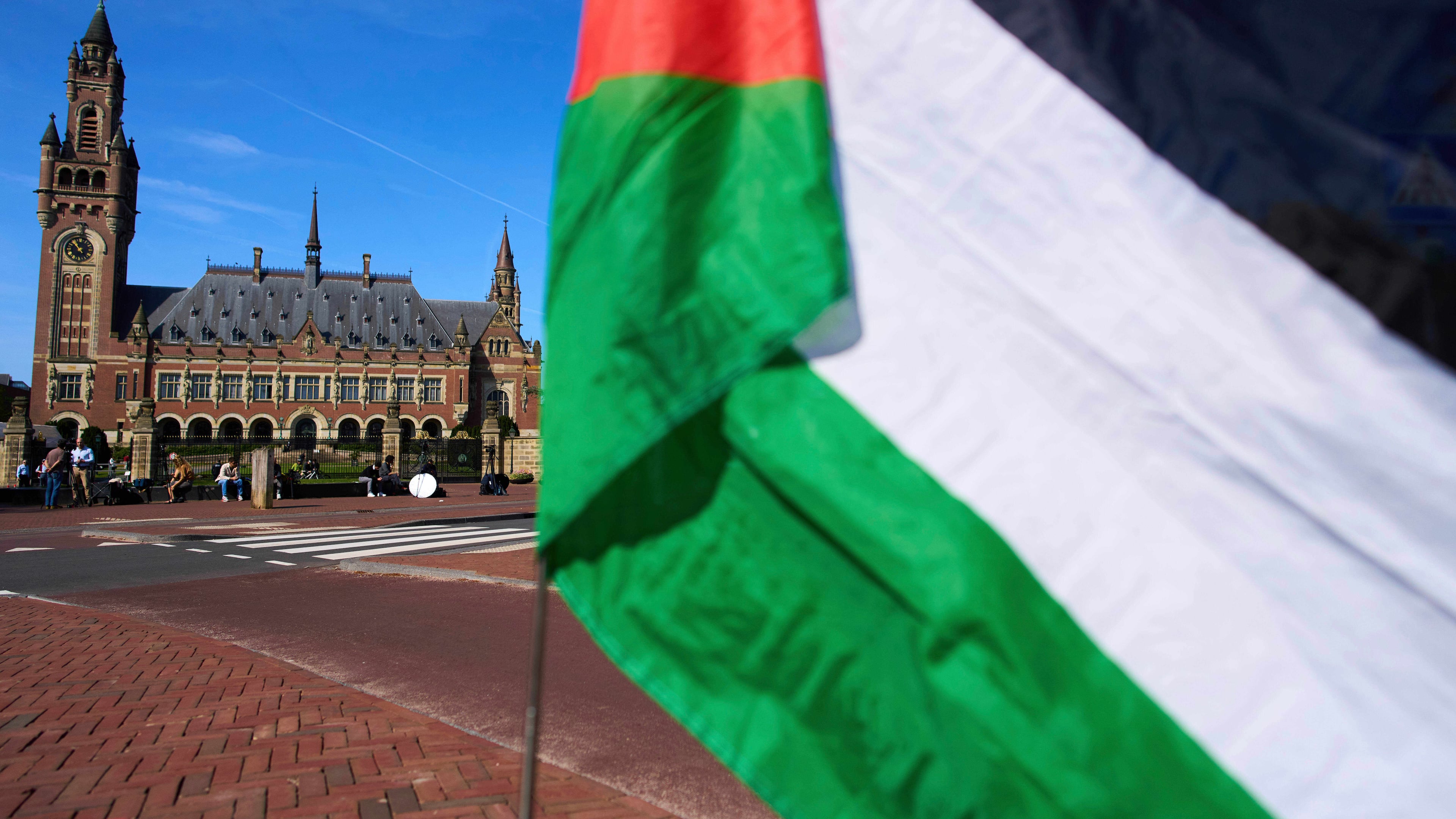 FILE -A Palestinian flag flies outside the International Court of Justice, rear, which opened hearings into a United Nations request for an advisory opinion on Israel's obligations to allow humanitarian assistance in Gaza and the West Bank, in The Hague, Netherlands, April 28, 2025. (AP Photo/Peter Dejong, File)