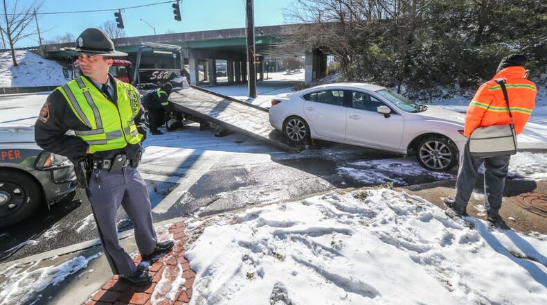 January 17, 2018 Atlanta: GSP trooper S. Stone (left) waits on a Mazda 6 to be towed from the scene after James May (right) skidded on the ice on Joseph E. Lowery Blvd. striking a concrete sewer on the I-20 entrance ramp and breaking his axle. No one was hurt. JOHN SPINK/JSPINK@AJC.COM