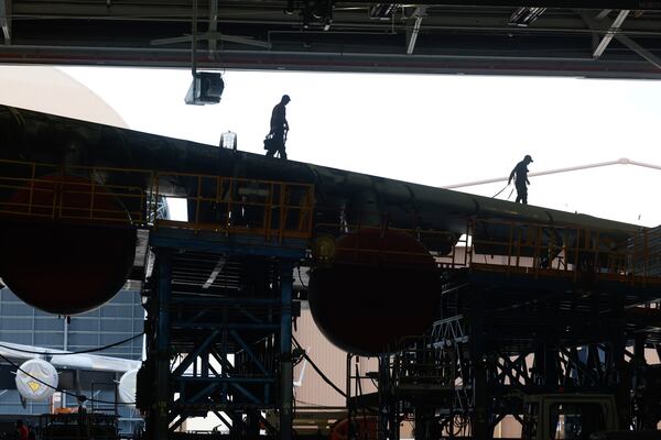 Workers walk on the wing of a C-5 aircraft under repair at a hangar in Robins Air Force Base in Houston County on Friday, Aug. 21, 2026. (Arvin Temkar/AJC)