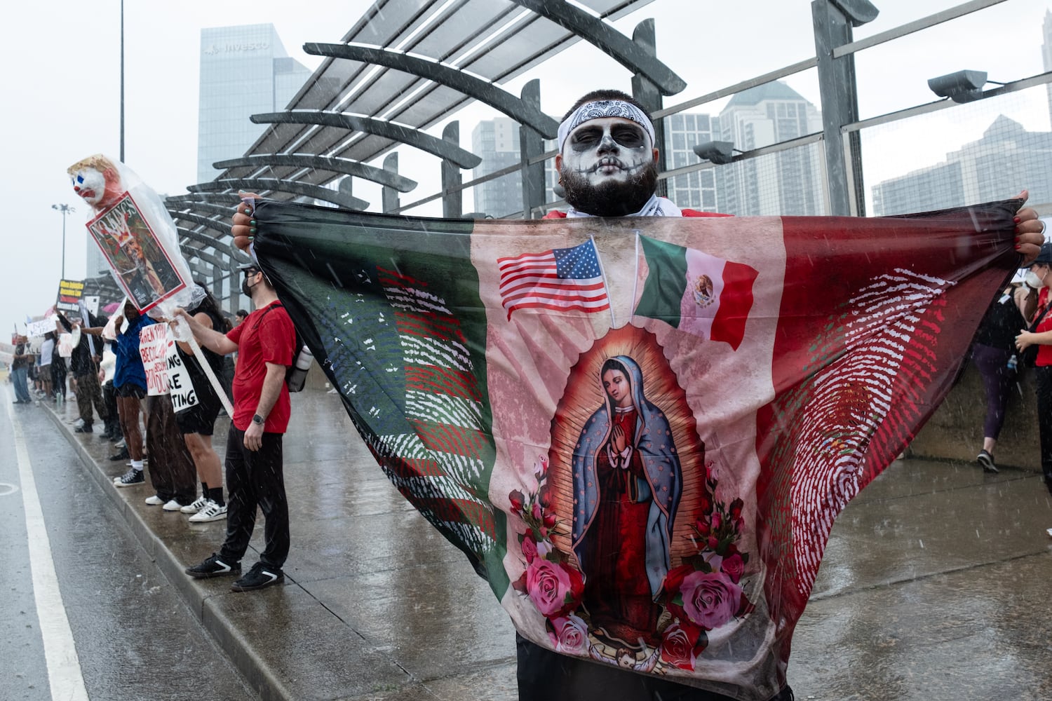 People brave the driving rain on the 17th Street bridge in Atlanta as part of the nation-wide No Kings protests Saturday, June 14, 2025.   Ben Gray for the Atlanta Journal-Constitution