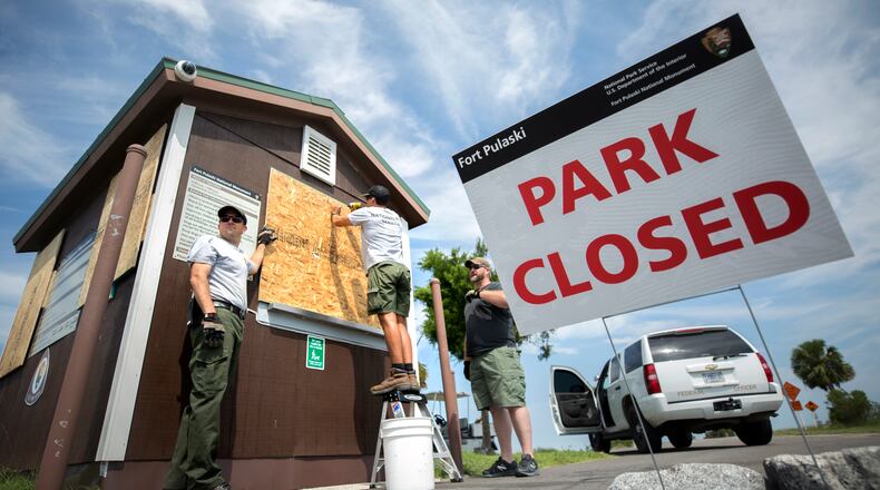 National Park Service employees screw in particle board to the secure the windows of the entrance station at Fort Pulaski National Monument near Tybee Island, Ga., Friday, Sept., 8, 2017, before Hurricane Irma is forecast to hit the area early next week. (Stephen B. Morton for The Atlanta Journal Constitution)