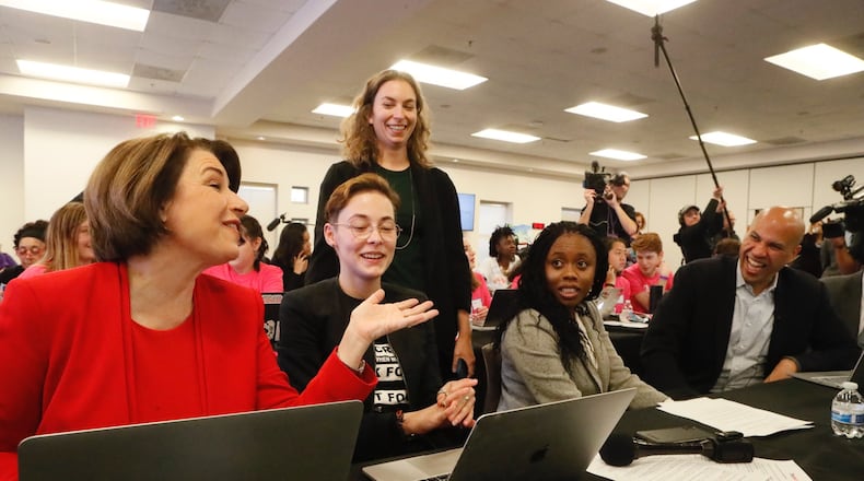 Democrats running for president, including U.S. Sens. Amy Klobuchar (left) and Cory Booker (right), used computers to send text messages to people whose Georgia voter registrations could be canceled on Thursday, Nov. 21, 2019. BOB ANDRES / robert.andres@ajc.com