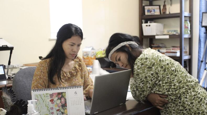 Veronica Thang helps Mary Maan, a Lilburn resident, with an immigration application at a temporary office space in Clarkston. (Courtesy of Sophia Qureshi)