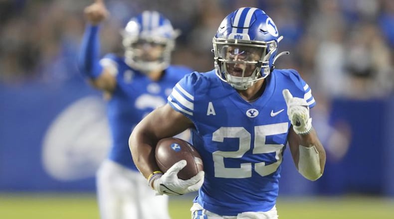 BYU running back Tyler Allgeier (25) runs for a touchdown as BYU quarterback Jaren Hall (3) celebrates during the first half of an NCAA college football game against Virginia Saturday, Oct. 30, 2021, in Provo, Utah. (AP Photo/George Frey)