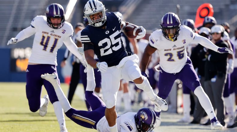 BYU running back Tyler Allgeier (25) runs the ball for a first down past North Alabama cornerback Will Singleton, bottom, defensive end Tyler Antkowiak (41) and linebacker Christon Taylor (25) in the second quarter during an NCAA college football game Saturday, Nov. 21, 2020, in Provo, Utah. (AP Photo/Jeff Swinger, Pool)