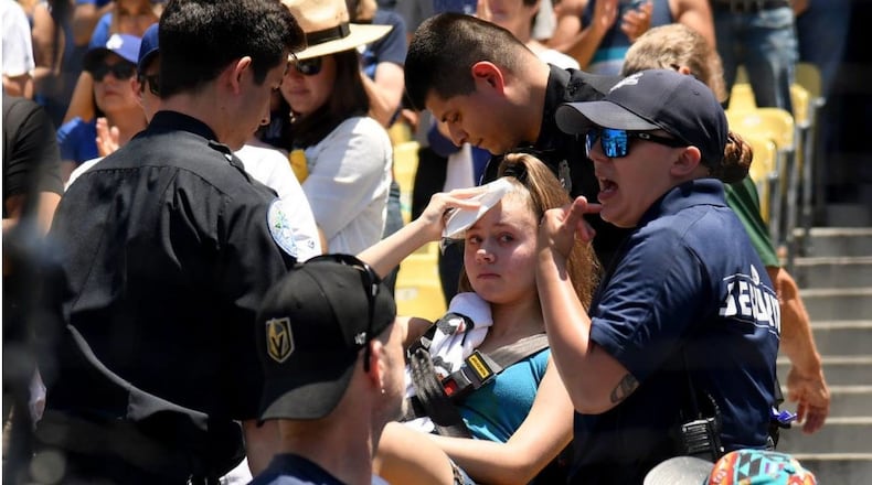 A young woman holds an ice pack to her head as she is taken by a stretcher from her seat at Dodger Stadium on Sunday. The fan was hit by a foul ball off the bat of Dodgers rightfielder Cody Bellinger.