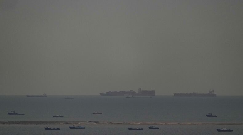 Fishing boats dot the sea as cargo ships, in the background, sail through the Arabian Gulf toward the Strait of Hormuz off the United Arab Emirates, Friday, March 27, 2026. (AP Photo)