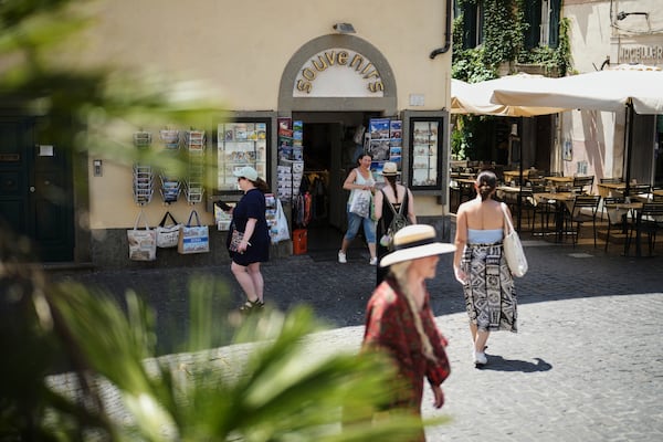 People walk past a souvenir shop in the town of Castel Gandolfo, a historic summer retreat for popes about 30 kilometers southeast of Rome, where Pope Leo XIV will be spending a short period of rest, is seen Wednesday, July 2, 2025. (AP Photo/Andrew Medichini)
