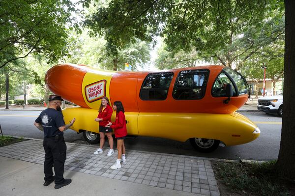 Hotdoggers Carly Bowden, center, and Evie Serda, center right, talks with members of the public after the Oscar Mayer Wienermobile toured the area on Aug. 18 in Atlanta.  (Jason Getz/AJC)