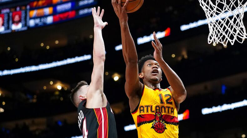 Hawks forward De'Andre Hunter (12) goes up for a shot as Miami Heat guard Tyler Herro (14) defends during the first half of an NBA basketball game Wednesday, Jan. 12, 2022, in Atlanta. Hunter was playing in his first game since undergoing wrist surgery. (AP Photo/John Bazemore)