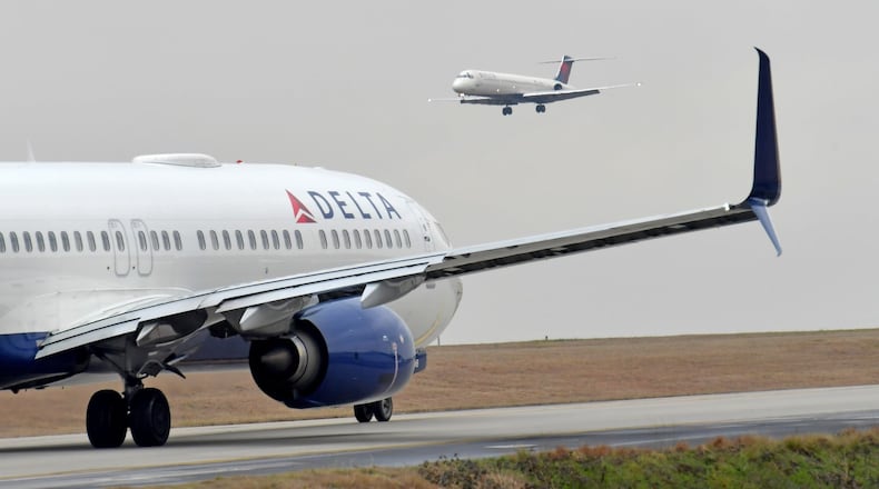 A Delta Air Lines jet prepares to take off as another jet approaches at Hartsfield-Jackson International Airport. HYOSUB SHIN / HSHIN@AJC.COM