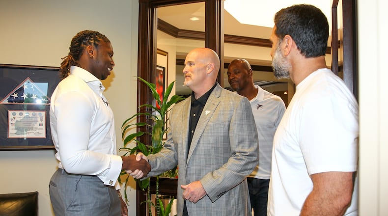 Falcons coach Dan Quinn shaking hands with first-round pick Takkarist McKinley on Sunday outside of his office. Family member in the background and linebackers coach Jeff Ulbrich to the right. (AtlantaFalcons.com)
