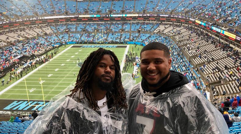 Falcons fans Benjamin Williams (left) and Kendrick Hawkins stand atop the upper bowl of Bank of America Stadium in Charlotte, North Carolina, during the Falcons-Panthers game Dec. 17, 2023. Hawkins received tickets for the game as a birthday present. (AJC photo by Ken Sugiura)