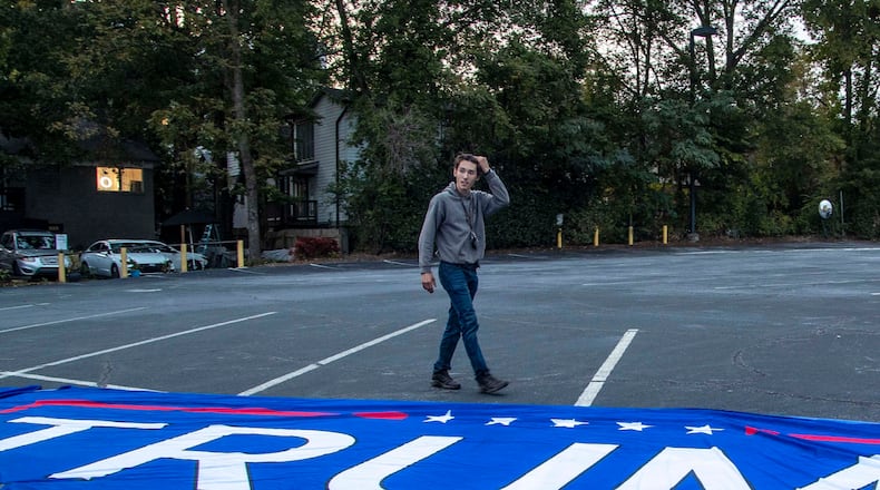 11/05/2020 — Atlanta, Georgia — Bruno Cua unfurls a large Trump flag during a rally in the parking lot at the Georgia Republican Party headquarters in Buckhead on Thursday, November 5, 2020. (Alyssa Pointer / Alyssa.Pointer@ajc.com)