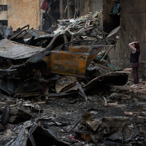 A resident checks damage to buildings as she walks near charred cars, at the site of Wednesday's Israeli airstrike, in Beirut, Lebanon, Friday, April 10, 2026. (AP Photo/Emilio Morenatti)