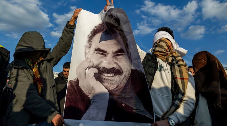 FILE - Youngsters hold a photograph of Abdullah Ocalan, the jailed leader of the militant Kurdish group, or PKK, in Diyarbakir, Turkey, Feb. 27, 2025. (AP Photo/Metin Yoksu, File)