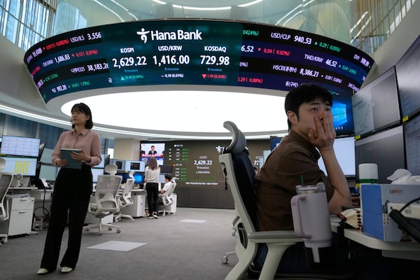 A currency trader watches monitors near a screen showing the Korea Composite Stock Price Index (KOSPI), top center left, and the foreign exchange rate between U.S. dollar and South Korean won, top center, at the foreign exchange dealing room of the KEB Hana Bank headquarters in Seoul, South Korea, Wednesday, May 14, 2025. (AP Photo/Ahn Young-joon)