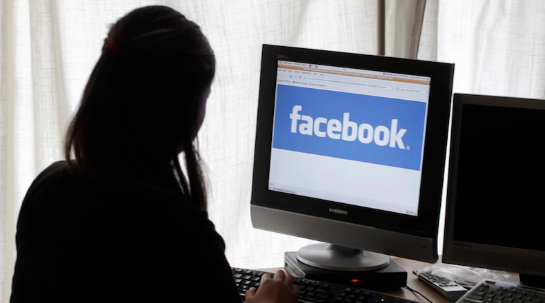 FILE - In this June 4, 2012 file photo, a girl looks at Facebook on her computer in Palo Alto, Calif. Baffled in 2016 by Russian agents who bought ads in an attempt to sway the U.S. presidential campaign, Facebook told the National Association of Secretaries of State on Saturday, Feb. 17, 2018, that the company would send postcards to potential buyers of political ads to confirm they reside in the U.S. The plan was unveiled a day after special counsel Robert Mueller charged 13 Russians with interfering in the presidential election. (AP Photo/Paul Sakuma, File)