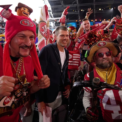 Former NFL player Andy Lee, center, poses with San Francisco 49ers fans during the second round of the NFL football draft, Friday, April 24, 2026, in Pittsburgh. (AP Photo/Sue Ogrocki)