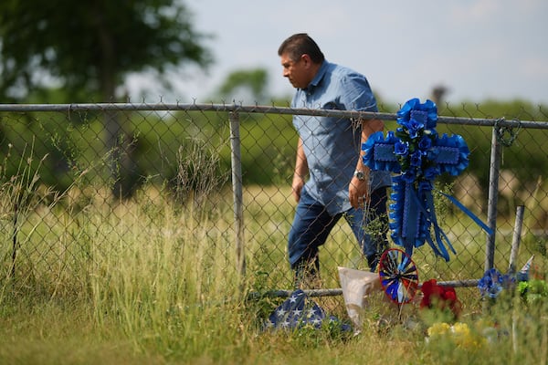 Adriane Reyes adds a cross to candles, flowers, and notes that create a make-shift memorial for voice actor Jonathan Joss who was recently killed, Tuesday, June 3, 2025, in San Antonio. (AP Photo/Eric Gay)