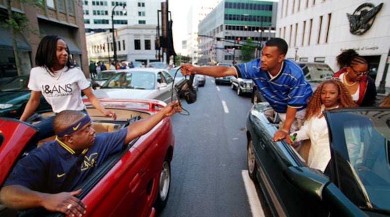 In this 1997 AJC file photo, Freaknik participants from New York pass off a video camera on Marietta Street.
