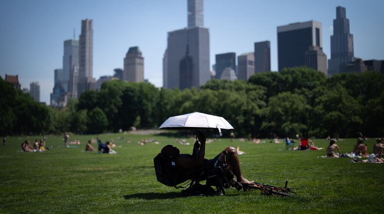 A person uses an umbrella to shield themselves from the sun during a heat advisory in Central Park, Tuesday, May 19, 2026, in New York. (AP Photo/Adam Gray)