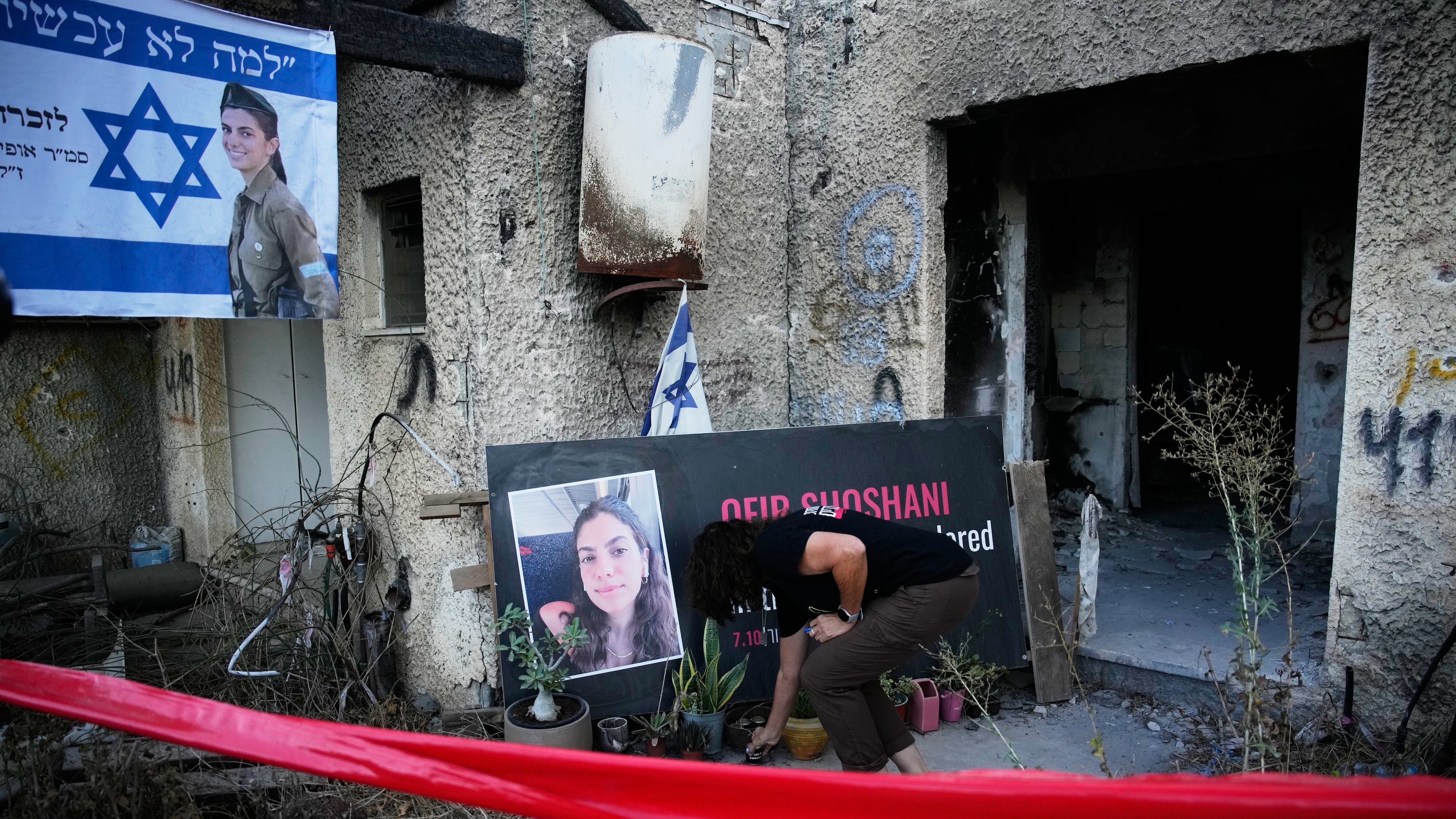 A woman places a candle at a tribute for Ofir Shoshani during a memorial marking two years since the deadly Hamas cross-border attack on Israel, in Kibbutz Kfar Aza, Tuesday, Oct. 7, 2025. (AP Photo/Ohad Zwigenberg)