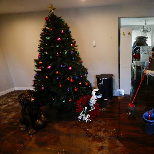Fracis Tarango mops inside her daughters' home damaged by floodwaters in Burlington, Wash., Saturday, Dec. 13, 2025. (AP Photo/Manuel Valdes)