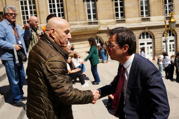Yunice Abbas, left, one of the men accused in the 2016 armed robbery of Kim Kardashian, shakes hands with his lawyer Gabriel Dumenil outside the palace of justice Monday, April 28, 2025 in Paris. (AP Photo/Aurelien Morissard)