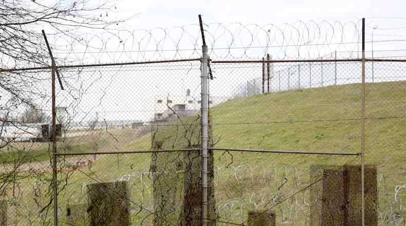Patches of metal cover holes that minimum-security inmates have cut into the fence around the Atlanta federal penitentiary's prison camp as they escaped and then sneaked back in. (David Barnes / For the AJC)