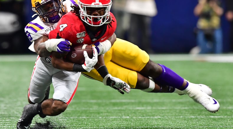 Georgia Bulldogs running back James Cook (4) is stopped by LSU Tigers linebacker K'Lavon Chaisson (18) during the second half of the Georgia vs. LSU SEC Football Championship game at Mercedes-Benz Stadium in Atlanta. Hyosub Shin / hyosub.shin@ajc.com