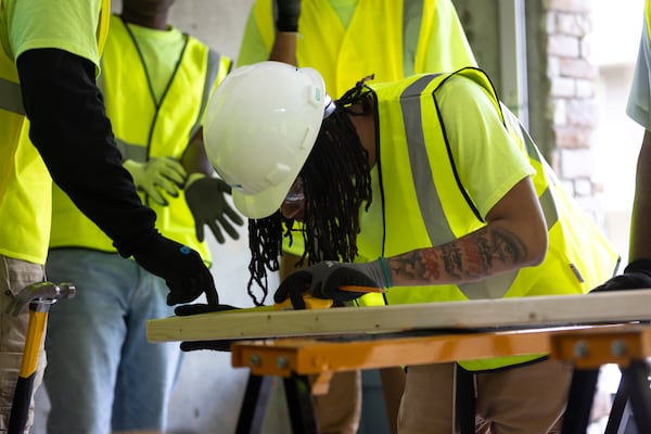 Isac Edwards, a student in the Construction Ready program, measures a piece of wood during a hands-on exercise at Westside Works in Atlanta. (Arvin Temkar/AJC)