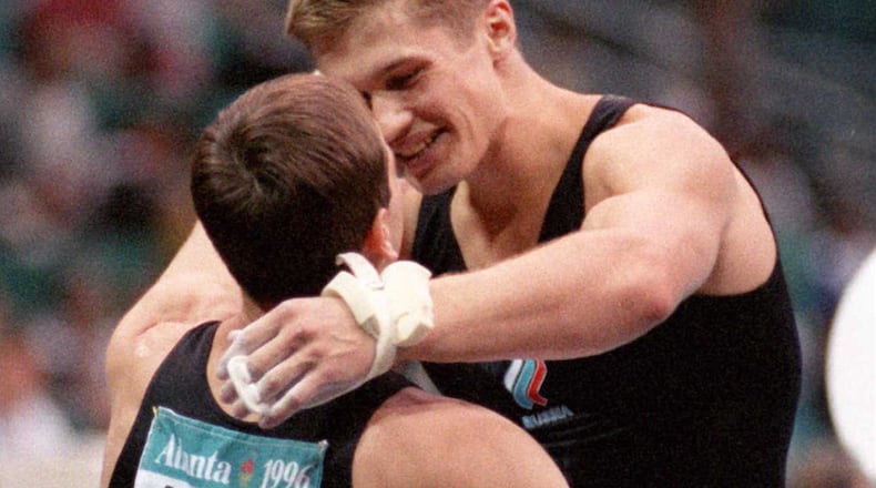 Russian teammates Alexei Nemov (background) and Alexei Voropaev, embrace after Nemov finished the horizontal bar to give the Russians the gold during the team competition finals Monday, July 22, 1996, during the Olympic Games at the Georgia Dome in Atlanta. (Karen Warren/Cox)