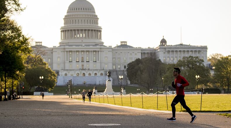 The U.S. Capitol Building is visible as a jogger makes their way across the National Mall, Wednesday, April 22, 2020, in Washington. (AP Photo/Andrew Harnik)