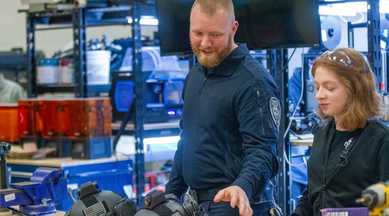 Cody Belcher, an investigator for the Lilburn Police Department, and Sarah Andrews, a senior at Maxwell High School of Technology, talk about the camera mount that Andrews designed for a team of local police officers Thursday, March 17, 2022. (Steve Schaefer for The Atlanta Journal-Constitution)