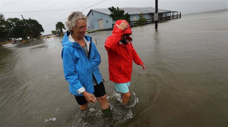 St. Marys residents Jen Fabrick (left) and Anne Herring (right) walk through flood waters covering a street near their homes as Hurricane Dorian passes near Georgia’s coast on Wednesday afternoon.   Curtis Compton/ccompton@ajc.com