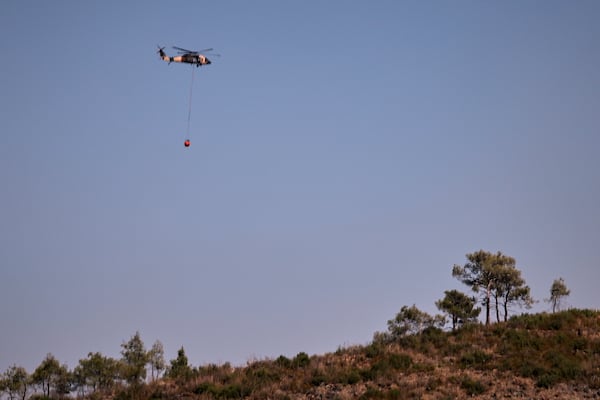 Jordanian Black Hawk helicopters carry out water-filling operations to help extinguish a wildfire near the town of Rabia, in Syria's Latakia countryside, Sunday, July 6, 2025. (AP Photo/Ghaith Alsayed)