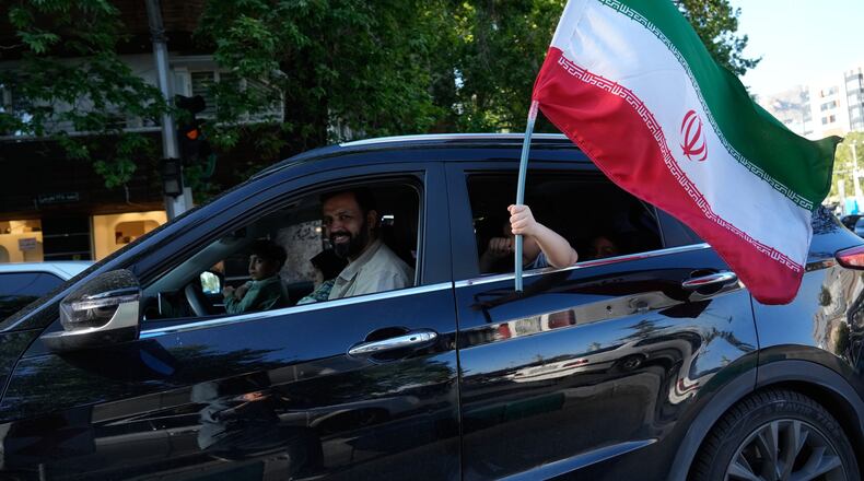 A child holds an Iranian flag through the window of a vehicle in northern Tehran, Iran, Friday, May 1, 2026. (AP Photo/Vahid Salemi)